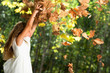 Girl playing with autumn leaves outdoors.