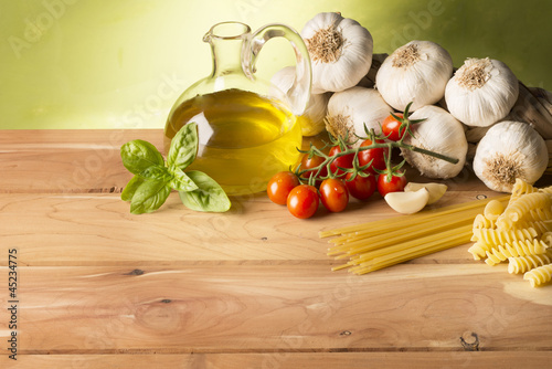 Photo: still life with olive oil,vegetables on wood table still life with olive oil,vegetables on wood table