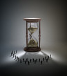 Tiny people standing around hourglass