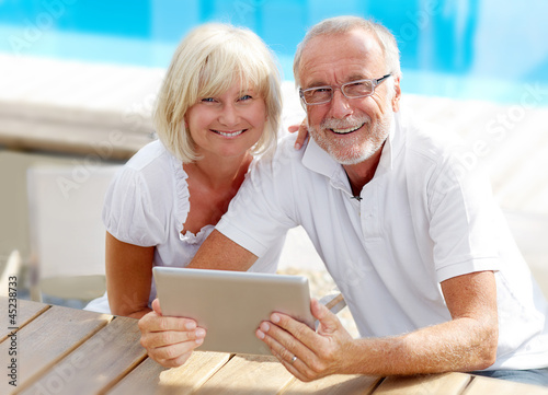 Photo: Different aged couple using a tablet pc outside Different aged couple using a tablet pc outside