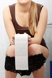 Woman sitting on a toilet holding toilet paper.