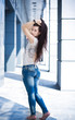 pretty girl in jeans posing against a modern building