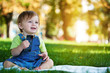 baby is playing with phone on the green grass