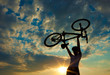 Biker holds bike high up in the sky