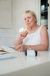 Photo: Mature woman checking bills and doing budget at home Mature woman checking bills and doing budget at home