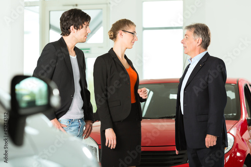 Photo: Älterer Mann mit Autos und jungem Pärchen im Autohaus Älterer Mann mit Autos und jungem Pärchen im Autohaus