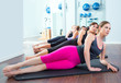 Pilates women group lying on mat with gym instructor