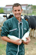 Farmer standing in front of cow herd with bottles of milk