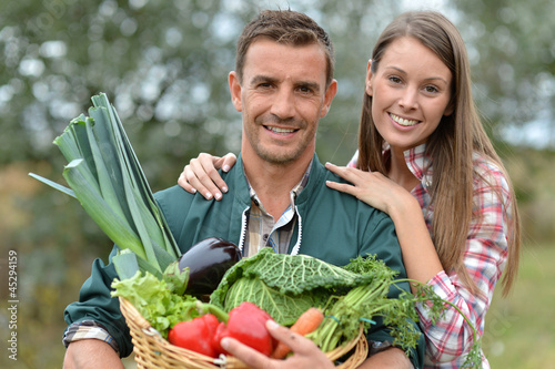Photo: Portrait of couple of farmers holding basket of vegetables Portrait of couple of farmers holding basket of vegetables