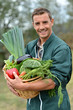 Portrait of smiling farmer holding vegetables basket