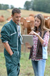 Farmer and woman in cow field using tablet