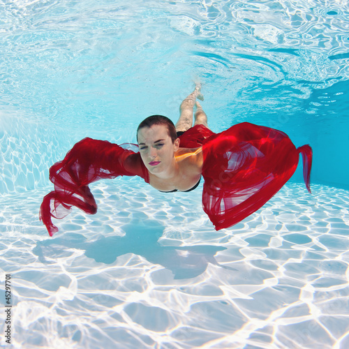 Photo: Underwater woman fashion portrait with red veil in swimming pool Underwater woman fashion portrait with red veil in swimming pool