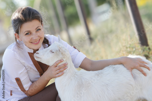 Photo: outdoor portrait of young happy woman with goat outdoor portrait of young happy woman with goat