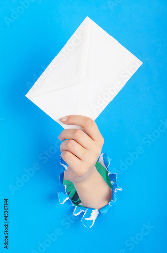 Photo: Hand holding paper envelope from hole Hand holding paper envelope from hole