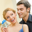 Cheerful amorous couple with gifts, indoors
