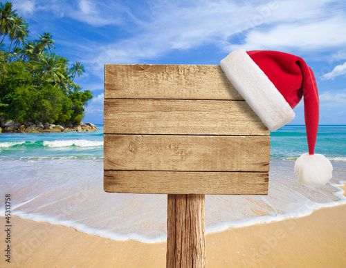 Photo: tropical beach wooden signboard with Christmas hat tropical beach wooden signboard with Christmas hat