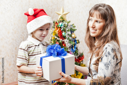 Photo: Mother and son with new year present or christmas holiday gift b Mother and son with new year present or christmas holiday gift b
