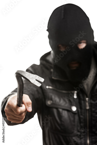 Photo: Criminal thief or burglar man in balaclava or mask holding crowb Criminal thief or burglar man in balaclava or mask holding crowb