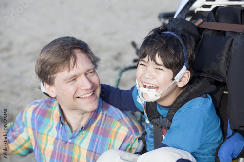 Photo: Father enjoying beach with disabled son Father enjoying beach with disabled son