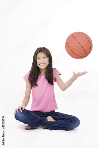 Photo: Ten year old Asian girl holding basketball, isolated on white Ten year old Asian girl holding basketball, isolated on white