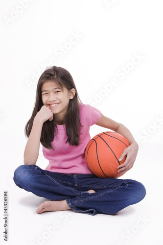 Photo: Ten year old Asian girl holding basketball, isolated on white Ten year old Asian girl holding basketball, isolated on white