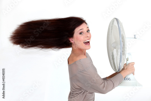 Photo: Brunette stood in front of fan Brunette stood in front of fan