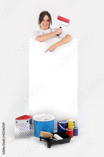 Photo: Female decorator stood pointing at blank poster Female decorator stood pointing at blank poster