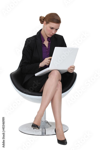 Photo: Businesswoman using a laptop in a chair Businesswoman using a laptop in a chair