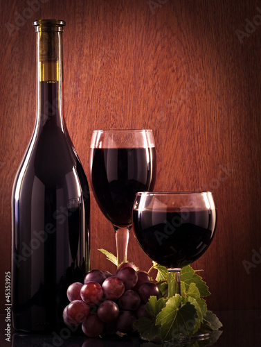 Photo: Red wine glass and Bottle on a wooden background Red wine glass and Bottle on a wooden background