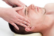 Young handsome man enjoying the facial massage on massage table
