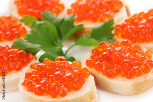 Photo: Red caviar on bread on white plate close-up Red caviar on bread on white plate close-up