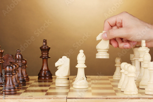 Photo: Chess board with chess pieces on brown background Chess board with chess pieces on brown background