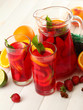 sangria in jar and glasses with fruits, on white wooden table