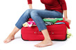 The girl is trying to close suitcase crammed on white
