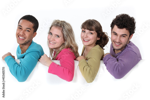 Photo: Young people leaning on white sign Young people leaning on white sign