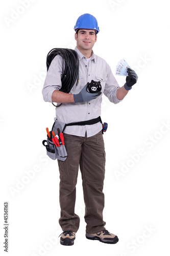 Photo: Construction worker holding a piggy bank and money Construction worker holding a piggy bank and money