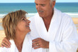 Couple wearing a bathrobe on a beach.