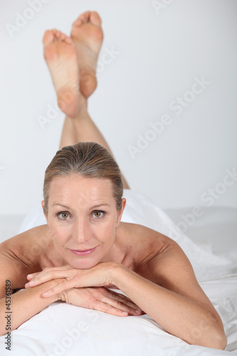 Photo: Woman lying naked under a white sheet Woman lying naked under a white sheet