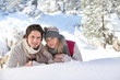 Couple laying on snowy hillside