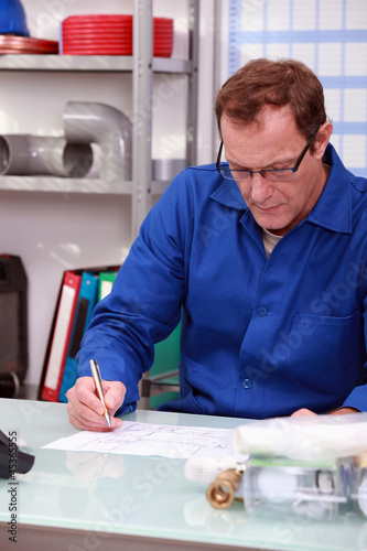 Photo: Plumber sat at desk Plumber sat at desk