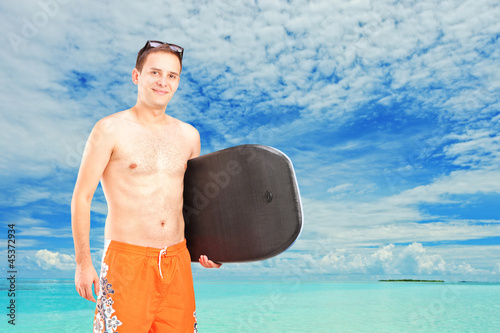 Photo: A male surfer posing with his surfboard A male surfer posing with his surfboard