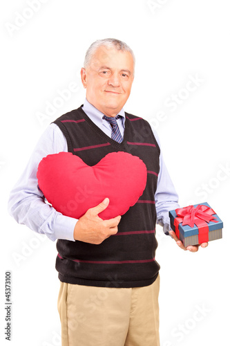 Photo: A mature gentleman holding a red heart shaped object and gift A mature gentleman holding a red heart shaped object and gift
