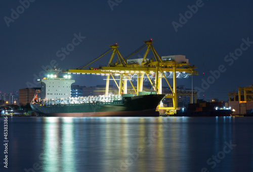 Photo: Container Cargo freight ship with working crane bridge in shipya Container Cargo freight ship with working crane bridge in shipya