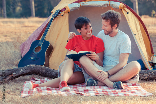 Photo: Young Couple Camping and Reading a Book Young Couple Camping and Reading a Book