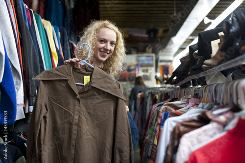 Photo: smiling girl with funny shirt at thrift store smiling girl with funny shirt at thrift store