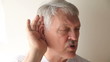 older man strains to hear what someone is saying