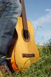 Wooden guitar resting on a mans foot in long green