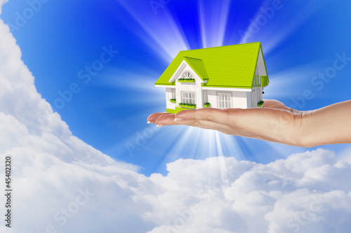 Photo: the house in hands on blue sky the house in hands on blue sky