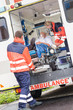 Paramedics putting patient in ambulance car aid