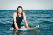 Young surf man relaxing in the water with a surfboard.